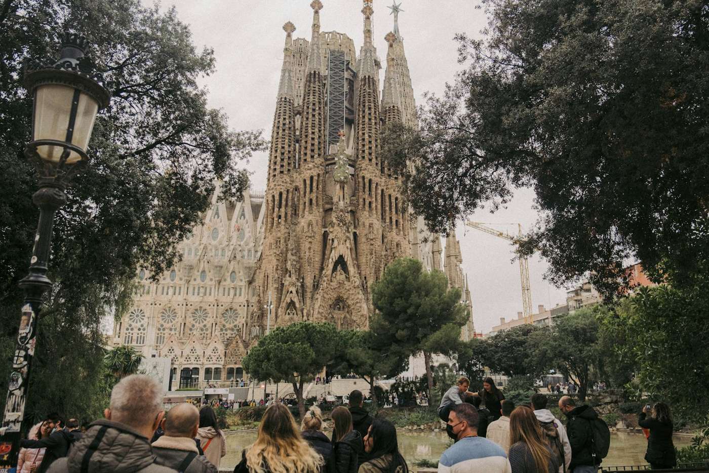 Besucher vor der Sagrada Família zwischen den Bäumen der Plaça de Gaudí